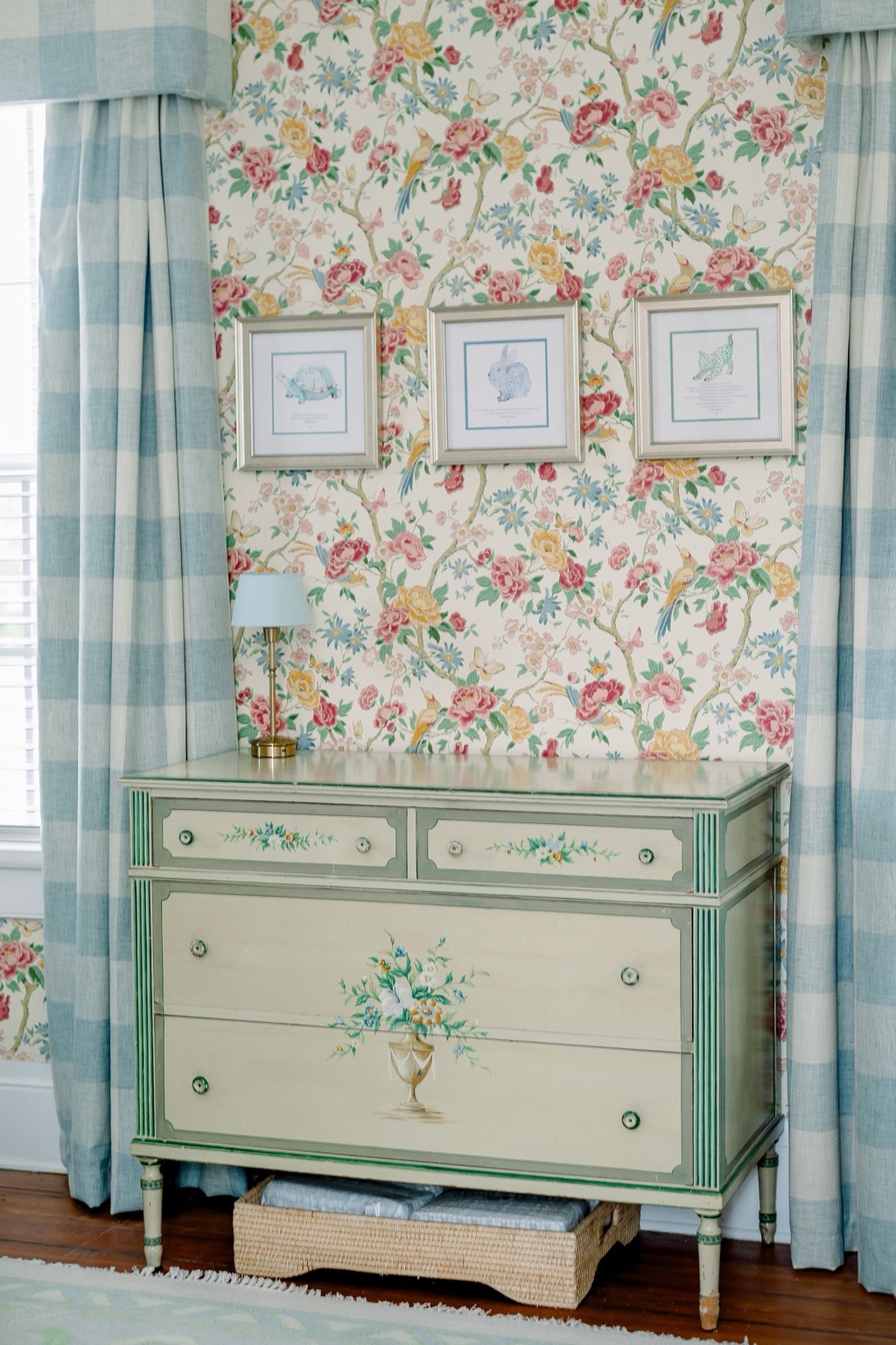 A collected nursery with patterned wallpaper, a crib, soft textiles, and warm natural light.
